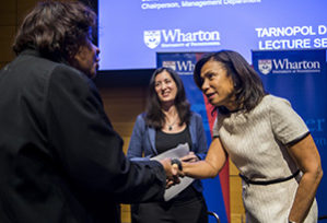 Edith Cooper shaking a woman's hand with Nancy Rothbard behind her