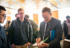 Howard Marks signs a copy of his book for an onlooking student