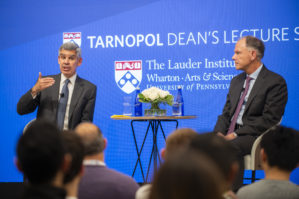 Mohamed A. El-Erian and Dean Geoff Garrett sit on a stage in conversation with an audience in the foreground