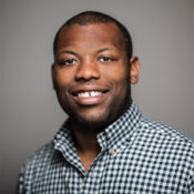 Headshot of a smiling person wearing a black and white checkered shirt.