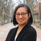 Headshot of a person wearing glasses, standing outdoors with trees and a path in the background.