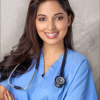 A person smiling in a professional headshot, wearing blue scrubs with a stethoscope draped around their neck, representing a healthcare professional.