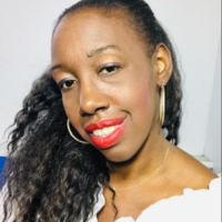 Headshot of a person with long hair and red lipstick, wearing hoop earrings and a white off-shoulder top, smiling slightly.